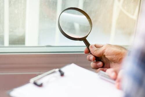 inspector holding magnifying glass over checklist