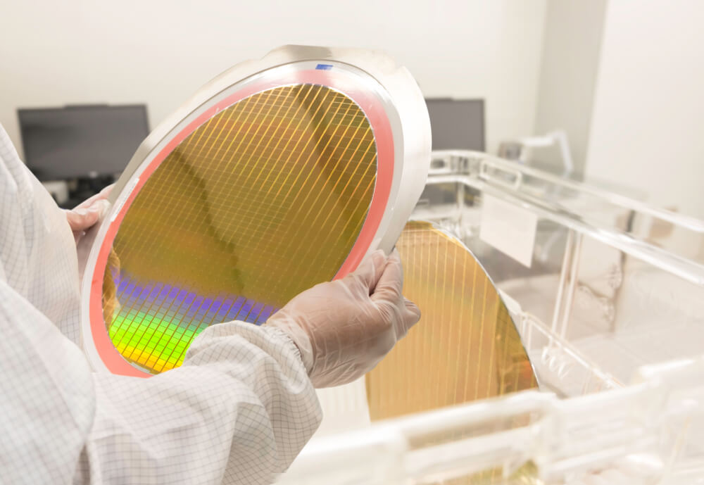 An engineer inspecting a wafer to avoid semiconductor fabrication challenges.